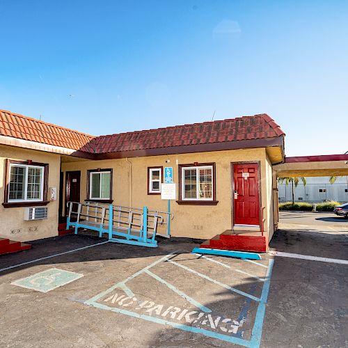 The image shows an outdoor view of a motel with red doors, handicap parking, and a 